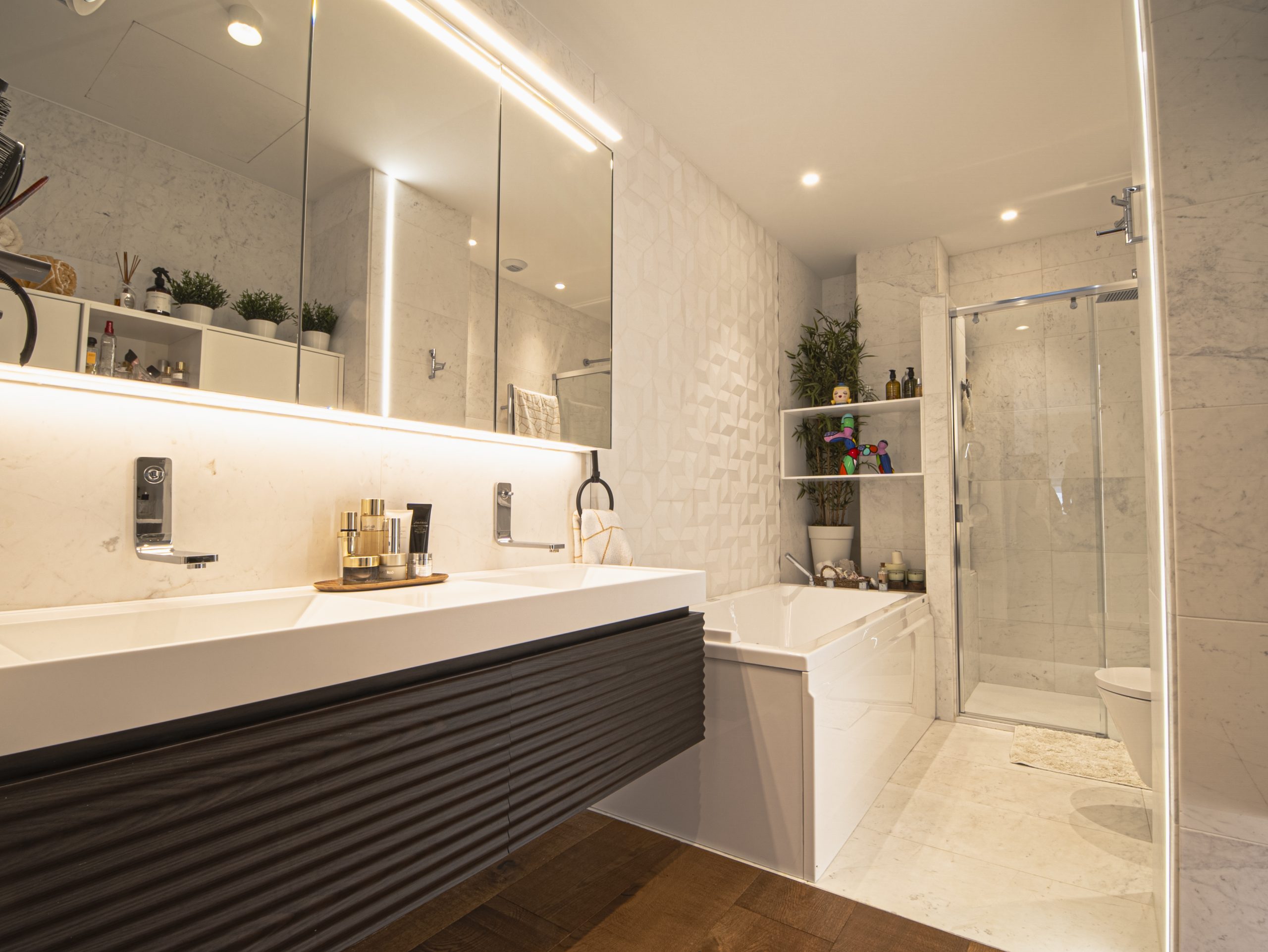 Baño con encimera blanca y luz lineal en una vivienda de lujo en Murcia