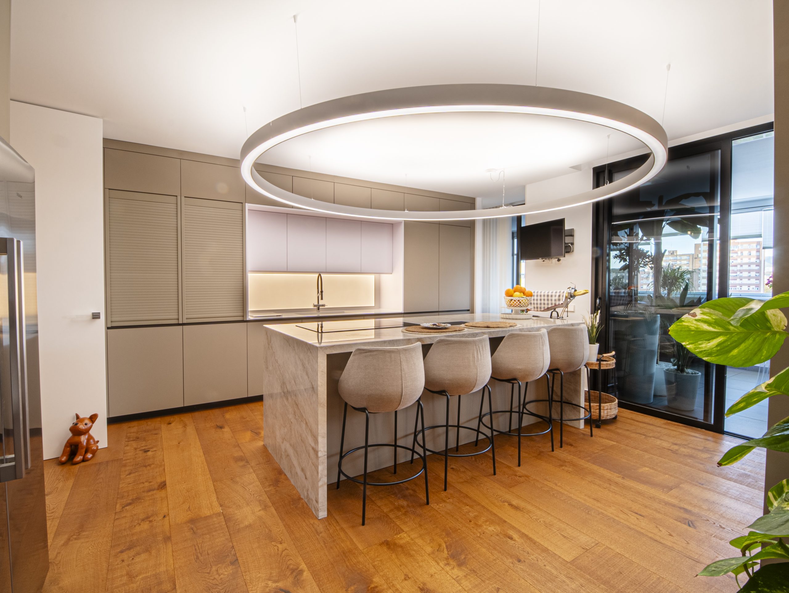 Cocina con barra y taburetes bajo una luminaria circular