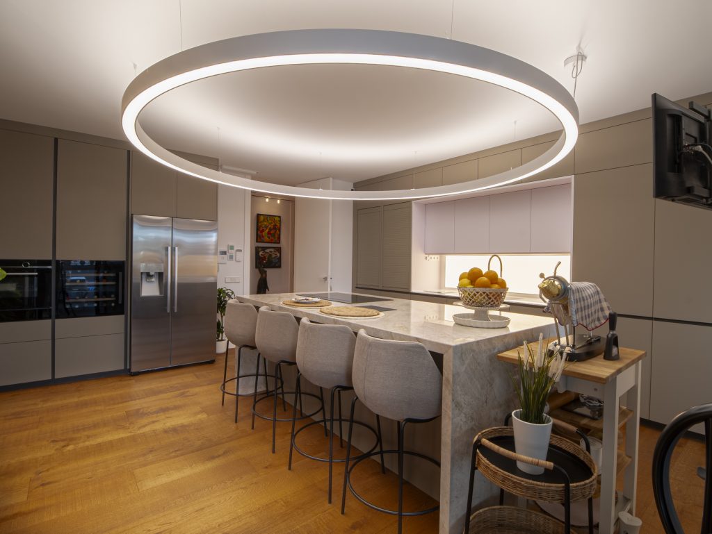 Cocina de obra nueva con isla central y luminaria circular, fotografiada por Airpro