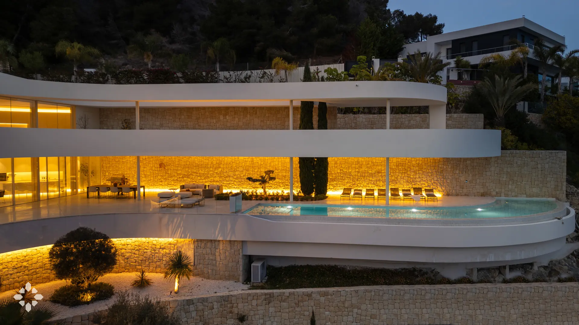 Villa iluminada al atardecer con piscina frente al mar