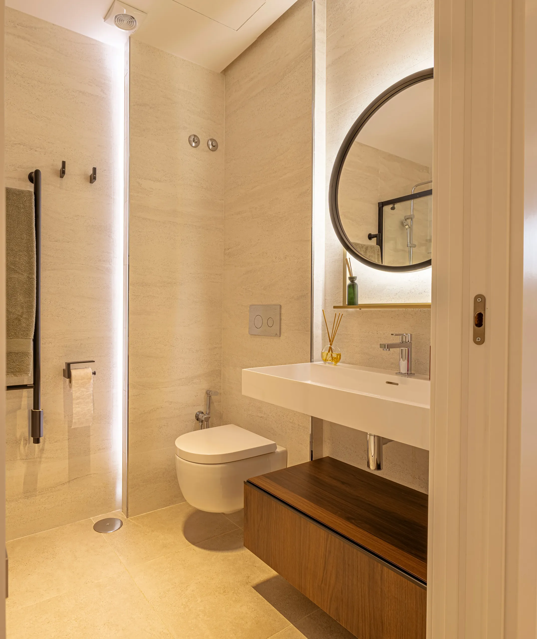 Baño con espejo redondo retroiluminado y mueble de madera en un ático