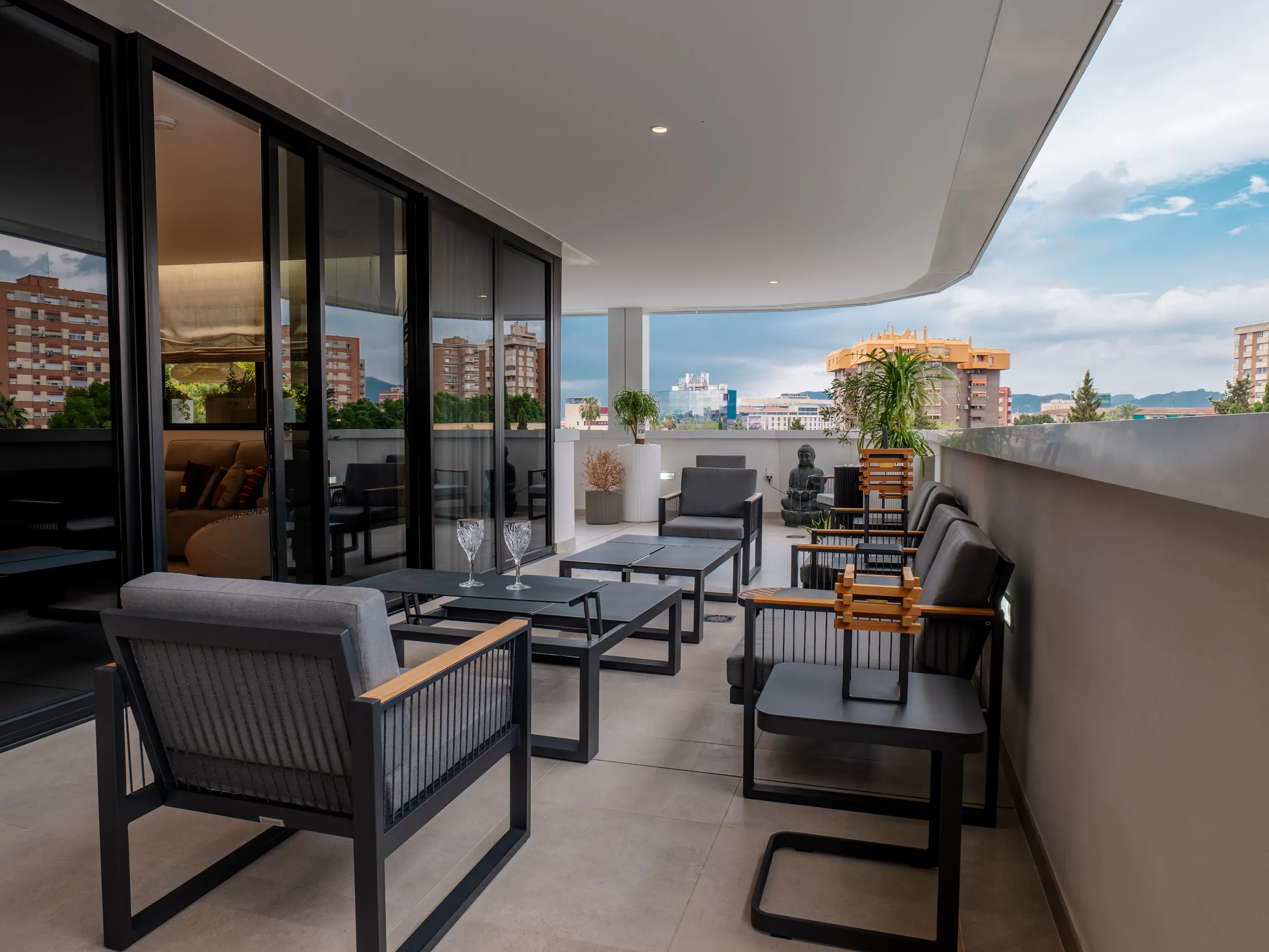 Salón exterior en la terraza cubierta de un ático con vistas a la ciudad