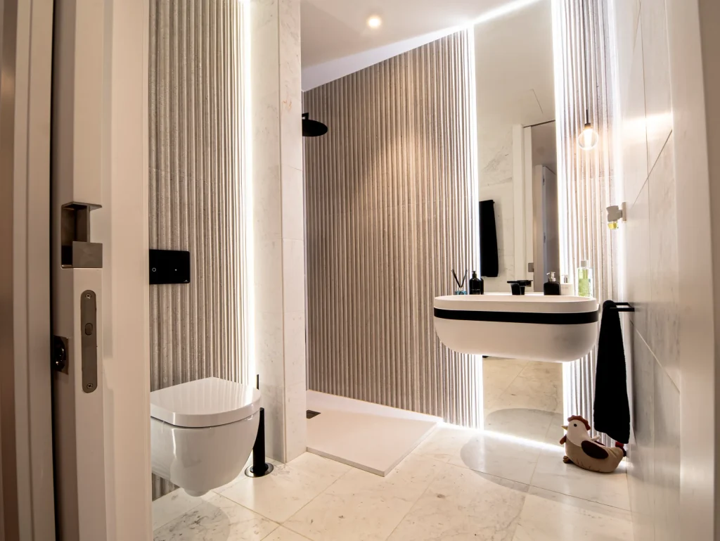 Baño con lavabo suspendido y ducha con luz lineal en una vivienda de lujo en Murcia