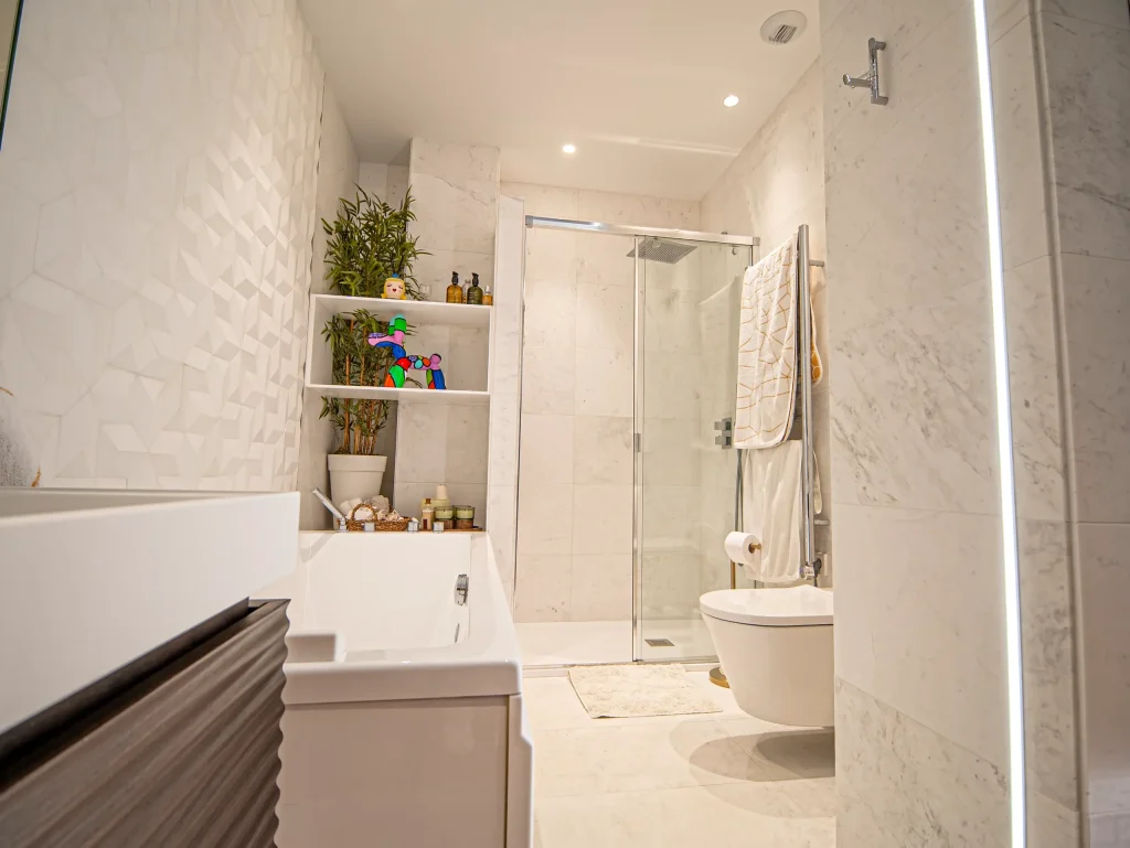Baño principal con bañera, ducha y pared de mármol en una vivienda de lujo en Murcia