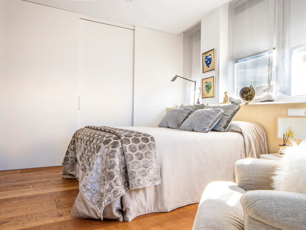 Dormitorio principal con cama tapizada y butaca en una vivienda de lujo en Murcia