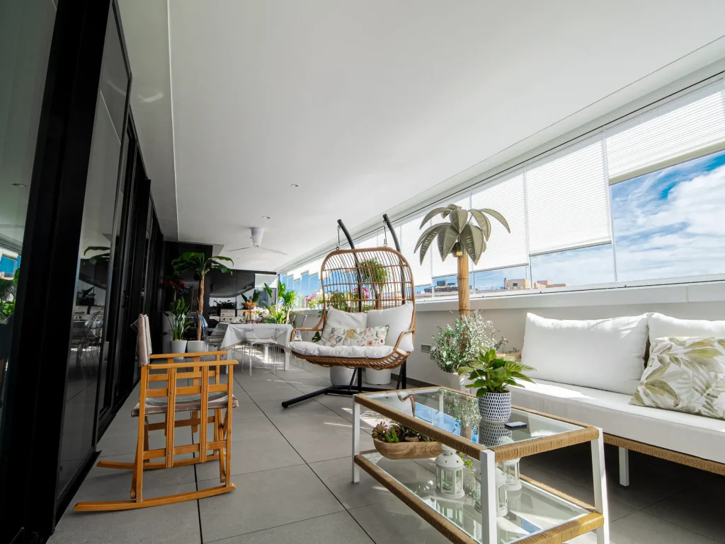 Terraza acristalada con balancín de mimbre en una vivienda de lujo en Murcia