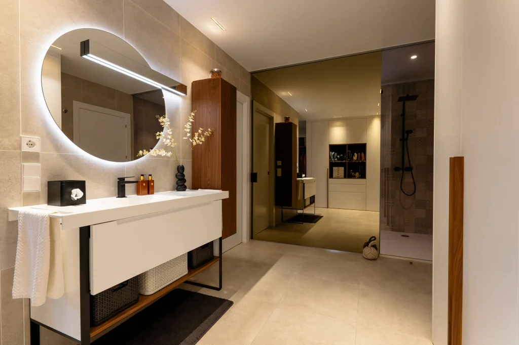 Baño con espejo redondo retroiluminado y mueble suspendido