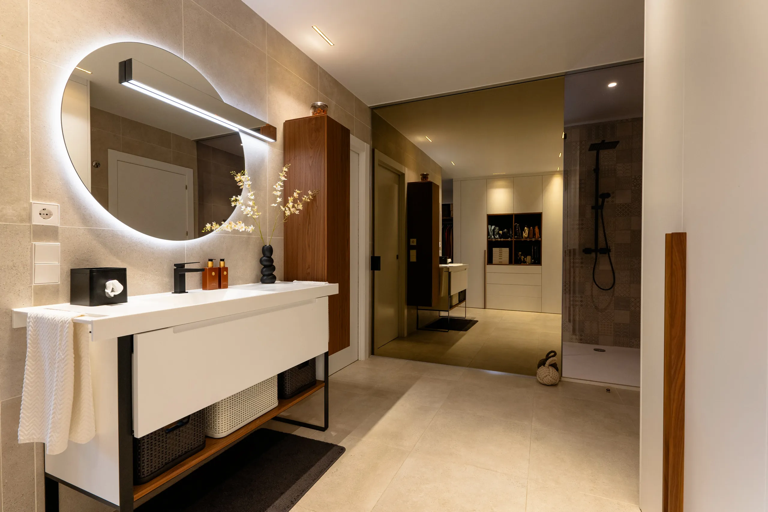 Baño con espejo redondo retroiluminado y mueble suspendido