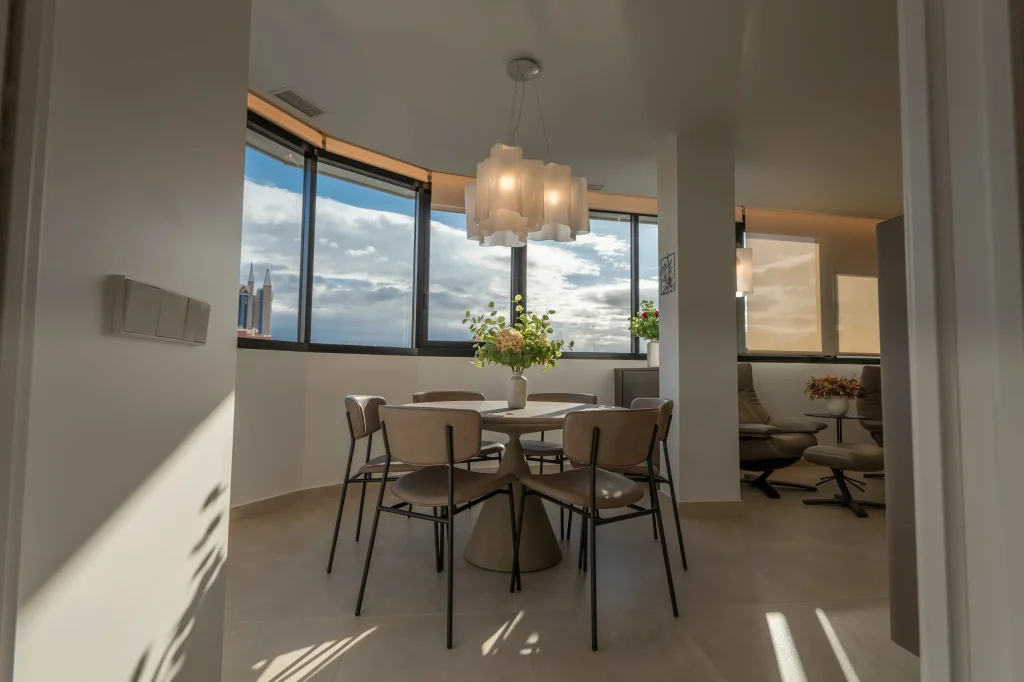 Mesa de comedor redonda junto a las ventanas con vistas a la ciudad