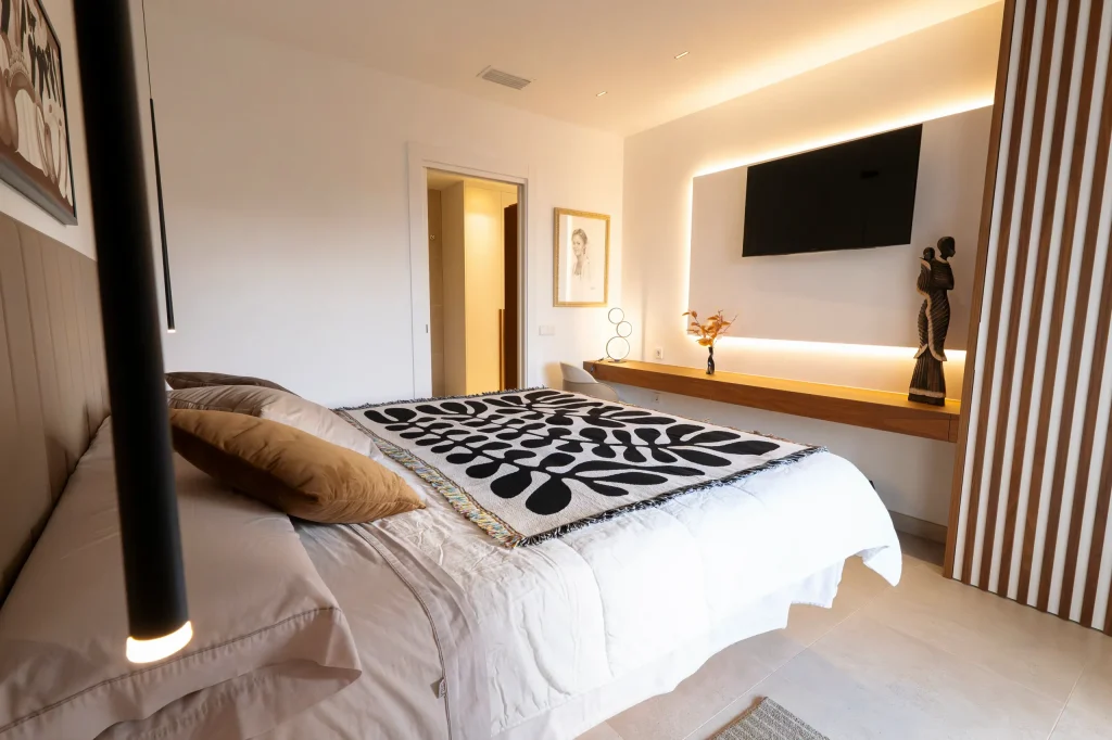 Dormitorio con panel de listones de madera y luz indirecta