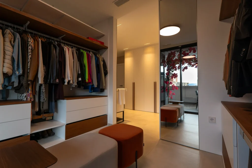 Vestidor abierto con módulos de madera y cajoneras blancas