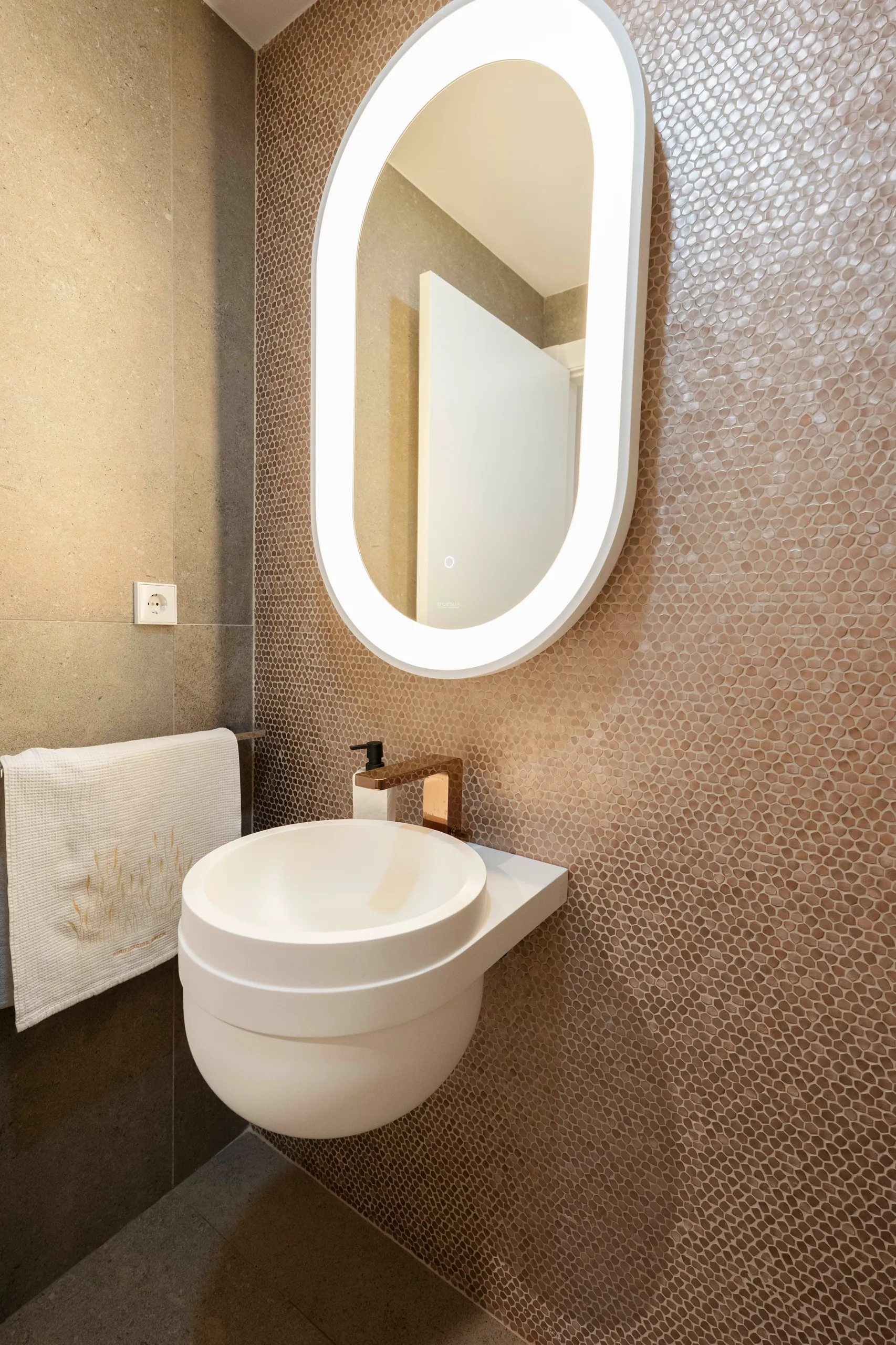 Lavabo de diseño con espejo ovalado retroiluminado y pared de gresite