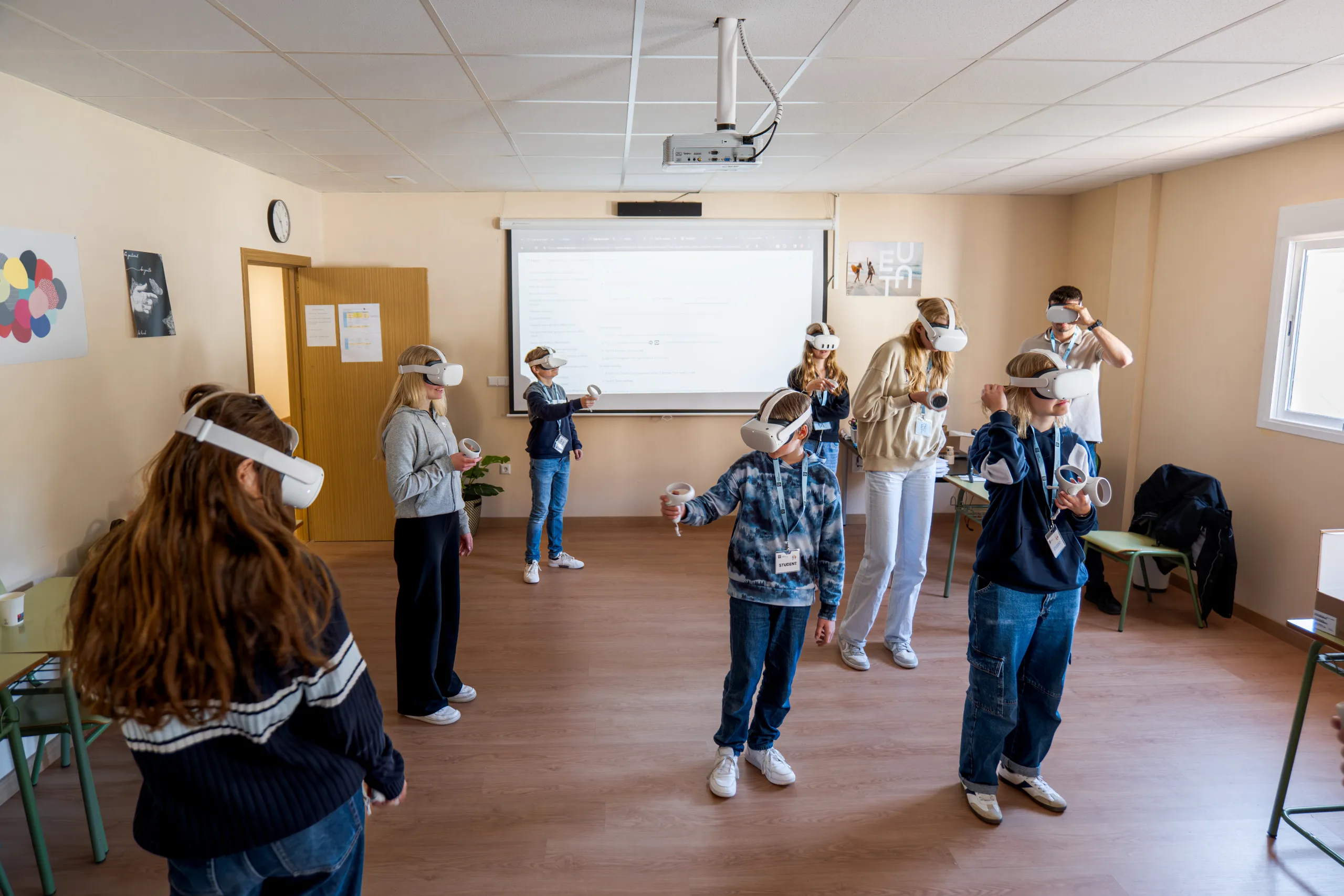 Alumna con gafas de realidad virtual en primer plano y sus compañeros practicando en clase