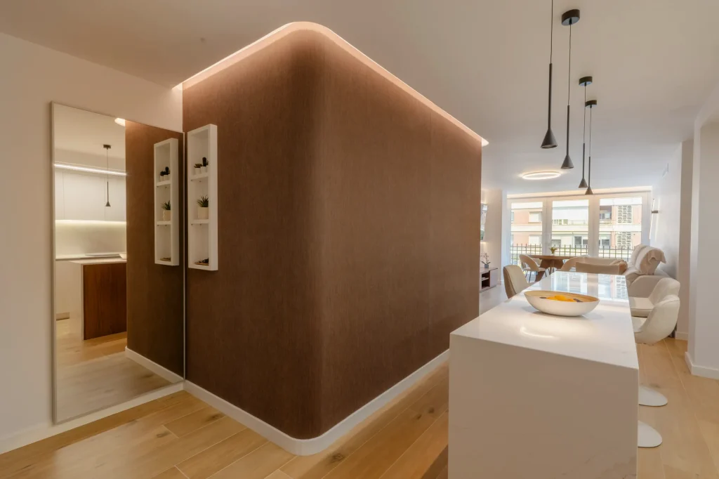 Volumen curvo de madera con luz indirecta junto a la cocina